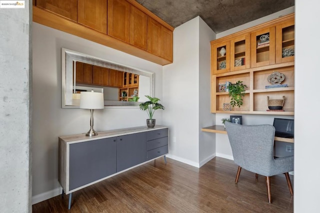 office with dark hardwood / wood-style flooring and built in desk