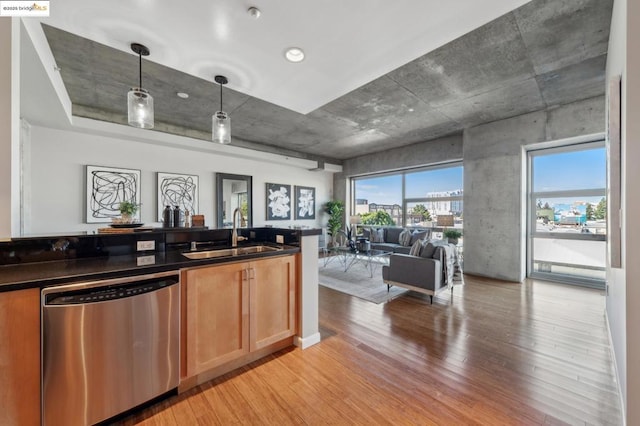 bar with dishwasher, sink, hanging light fixtures, light brown cabinets, and light wood-type flooring