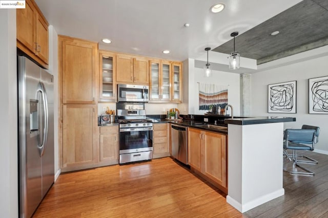 kitchen featuring appliances with stainless steel finishes, sink, a kitchen breakfast bar, hanging light fixtures, and kitchen peninsula