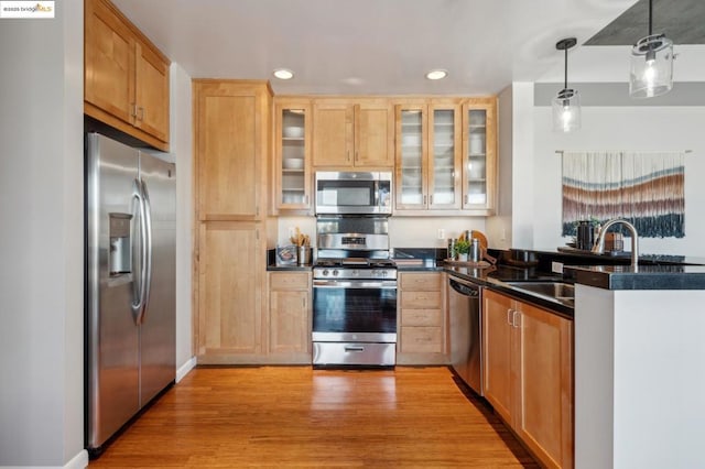 kitchen with light brown cabinetry, decorative light fixtures, sink, light hardwood / wood-style floors, and stainless steel appliances