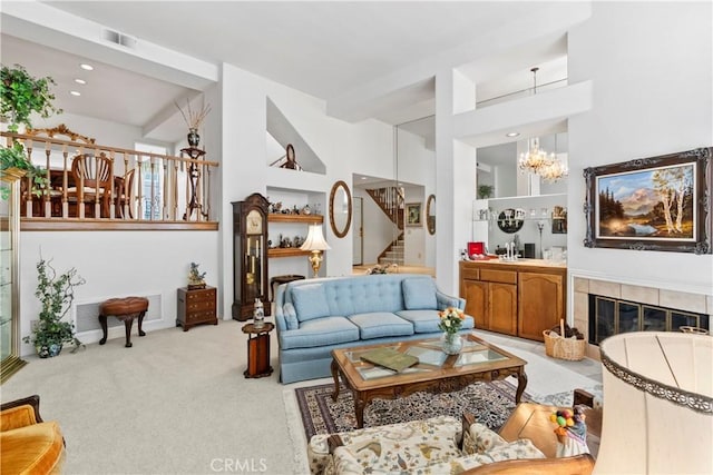 living room with a tiled fireplace, light carpet, and a chandelier