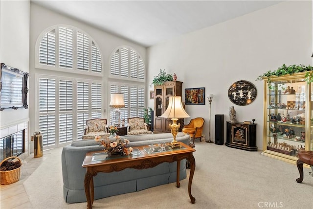 carpeted living room featuring a fireplace and a high ceiling