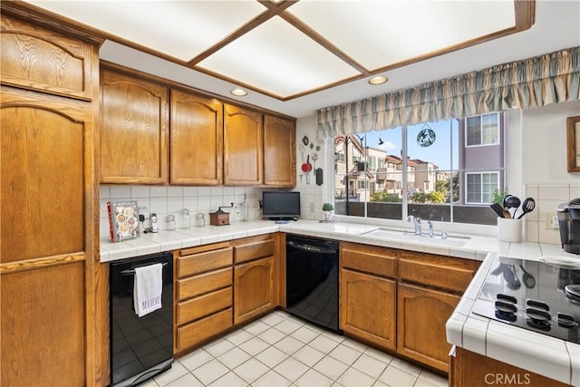 kitchen with light tile patterned flooring, sink, tasteful backsplash, tile countertops, and black dishwasher