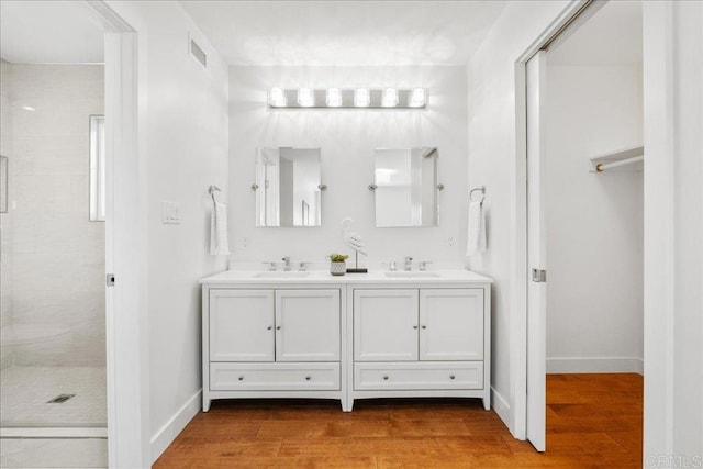 bathroom with tiled shower, wood-type flooring, and vanity