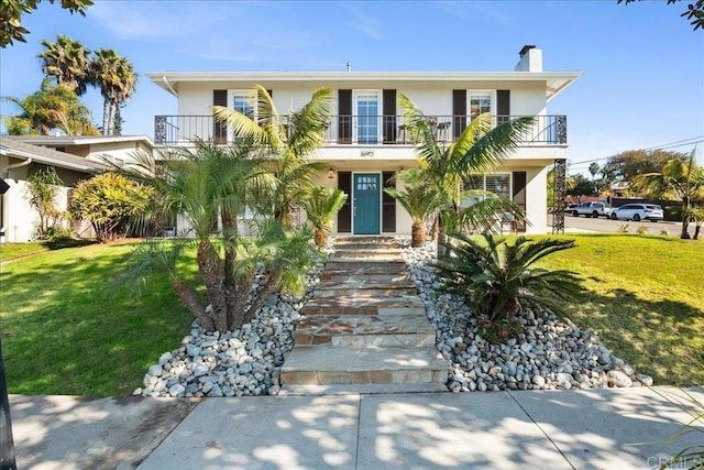 raised beach house with a front yard and a balcony