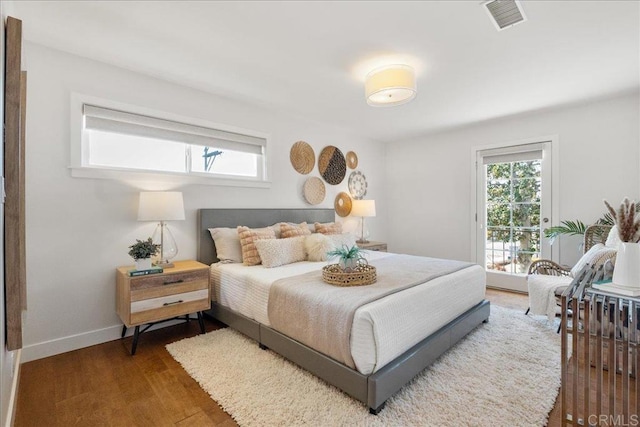 bedroom featuring multiple windows, dark hardwood / wood-style floors, and access to outside