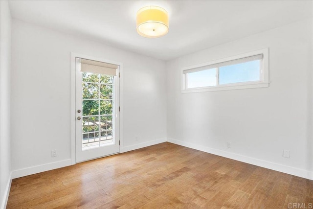 empty room with a wealth of natural light and light hardwood / wood-style floors