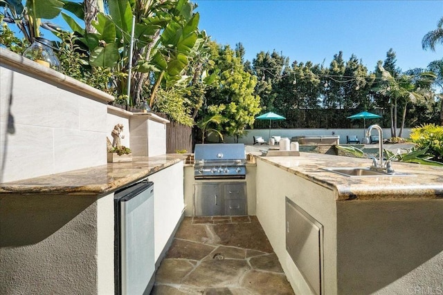 view of patio with an outdoor kitchen, a grill, and sink