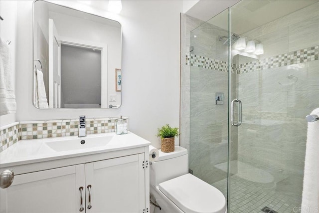 bathroom featuring vanity, decorative backsplash, a shower with door, and toilet