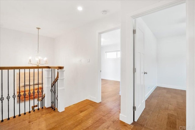 corridor with hardwood / wood-style floors and an inviting chandelier