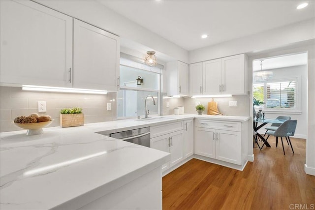 kitchen with white cabinetry, dishwasher, sink, decorative backsplash, and light wood-type flooring