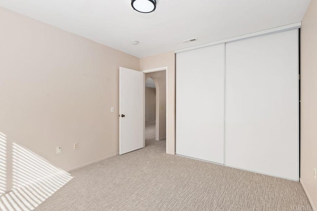 unfurnished bedroom with a closet and light carpet