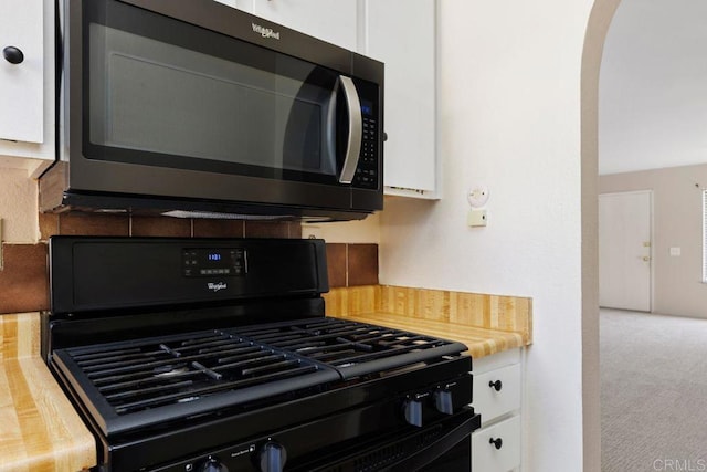 kitchen with black gas range, butcher block countertops, white cabinets, and carpet flooring