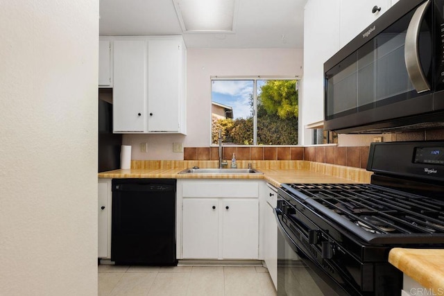 kitchen with light tile patterned flooring, white cabinets, sink, and black appliances