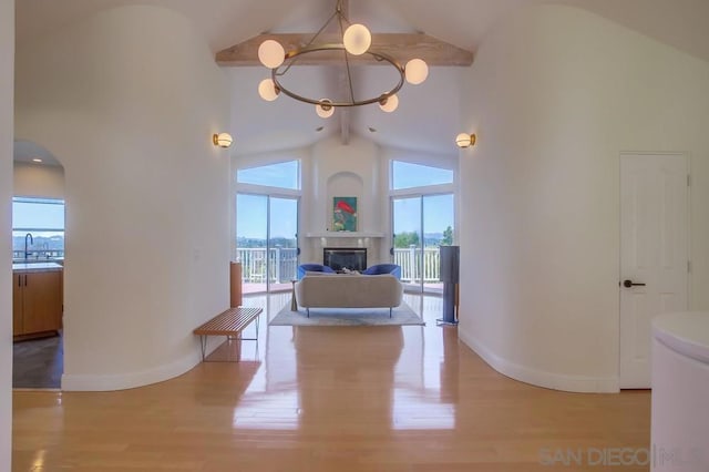 hall featuring beam ceiling, light hardwood / wood-style floors, high vaulted ceiling, and a notable chandelier