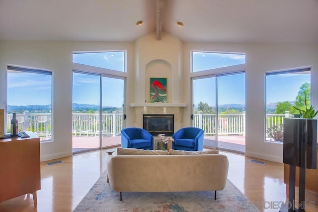 living room featuring beam ceiling, high vaulted ceiling, a fireplace, a mountain view, and light wood-type flooring