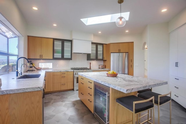 kitchen with sink, high quality appliances, a kitchen island, decorative light fixtures, and beverage cooler