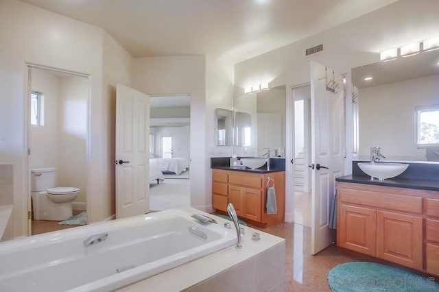 bathroom with vanity, tiled bath, and toilet