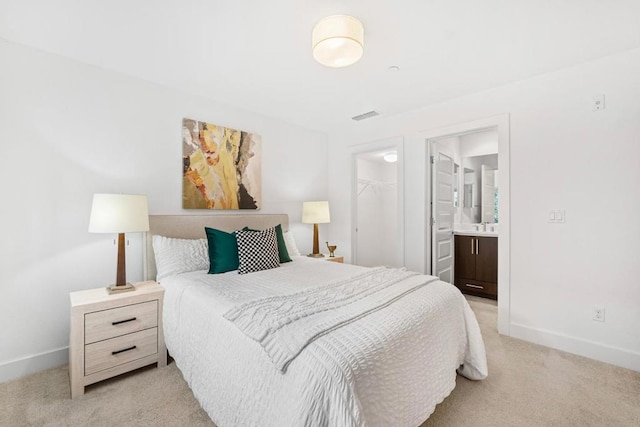 bedroom featuring light carpet, a spacious closet, ensuite bath, and a closet