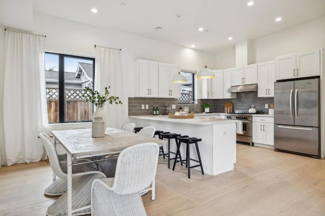 kitchen with a breakfast bar, white cabinetry, hanging light fixtures, kitchen peninsula, and stainless steel appliances