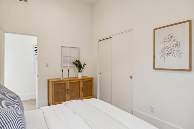 bedroom featuring a high ceiling, light hardwood / wood-style flooring, and a closet