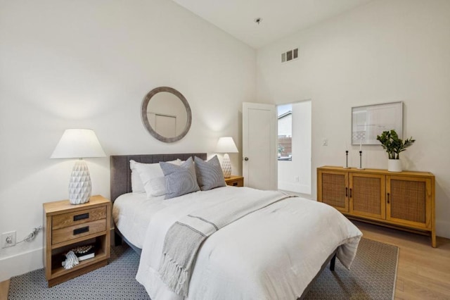 bedroom featuring high vaulted ceiling and light hardwood / wood-style floors