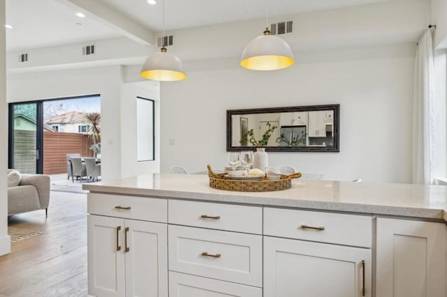 interior space featuring beam ceiling, light stone countertops, hanging light fixtures, and white cabinets