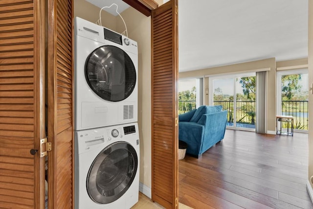 washroom with hardwood / wood-style flooring and stacked washer / dryer