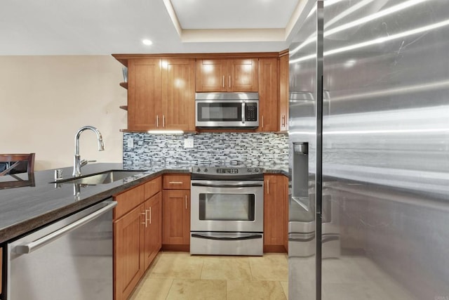 kitchen featuring sink, dark stone countertops, light tile patterned floors, stainless steel appliances, and backsplash