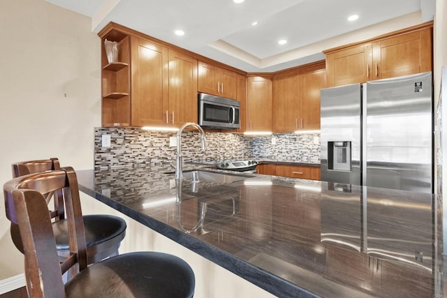 kitchen with a peninsula, stainless steel appliances, dark stone counters, and open shelves