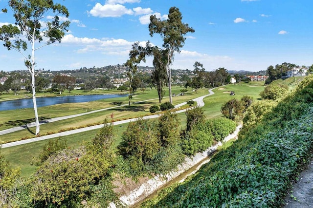 view of property's community with a lawn, a water view, and view of golf course