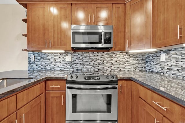 kitchen with tasteful backsplash, open shelves, dark stone countertops, appliances with stainless steel finishes, and brown cabinets