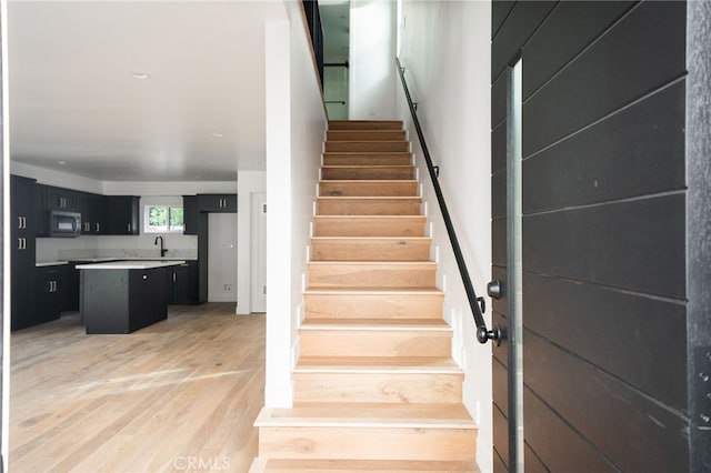 stairs featuring hardwood / wood-style floors and sink