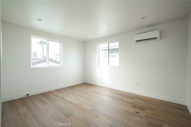 spare room with an AC wall unit and light hardwood / wood-style flooring