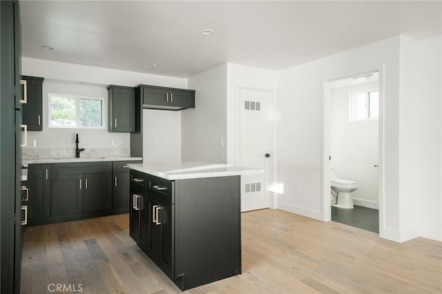 kitchen featuring a healthy amount of sunlight, a center island, sink, and light hardwood / wood-style flooring