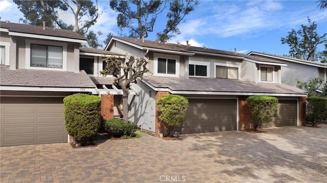 view of property with driveway, an attached garage, and stucco siding