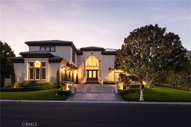 mediterranean / spanish-style house with french doors and a yard