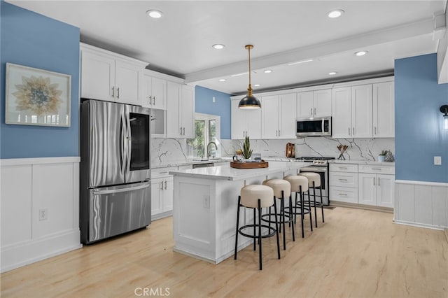 kitchen featuring white cabinetry, decorative light fixtures, stainless steel appliances, and a kitchen island