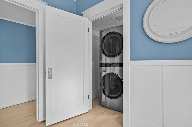 washroom with stacked washer and dryer and light wood-type flooring