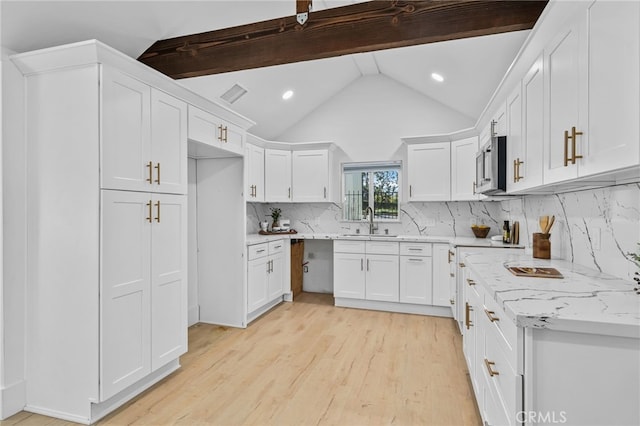 kitchen featuring lofted ceiling with beams, backsplash, light wood-type flooring, and white cabinets