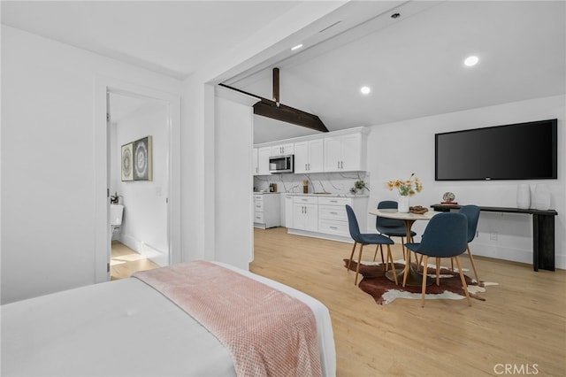 bedroom featuring lofted ceiling with beams and light hardwood / wood-style floors