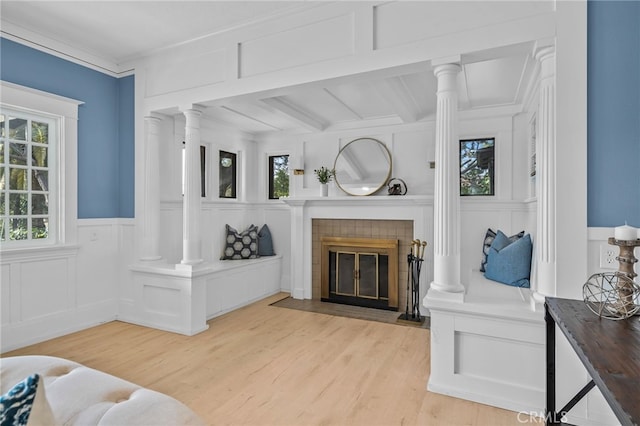 living room with ornate columns, ornamental molding, a fireplace, and light wood-type flooring