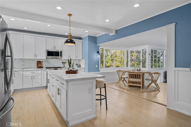 kitchen with light stone counters, decorative light fixtures, appliances with stainless steel finishes, a kitchen island, and white cabinets