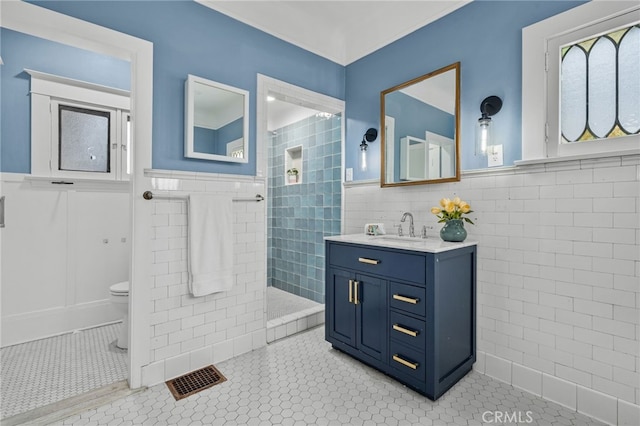 bathroom with tile patterned floors, toilet, vanity, and tile walls