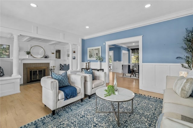 living room with ornate columns, crown molding, and light hardwood / wood-style floors