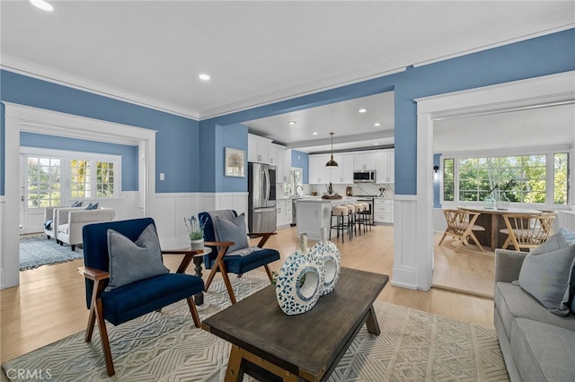 living room with crown molding, a healthy amount of sunlight, and light hardwood / wood-style floors