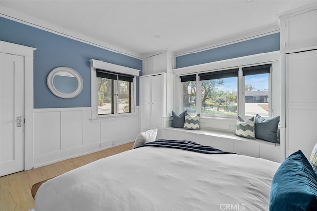 bedroom featuring multiple windows, crown molding, and light wood-type flooring