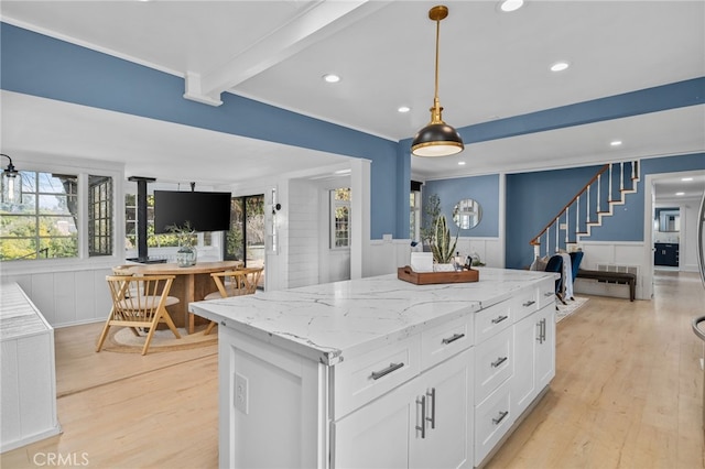 kitchen featuring light hardwood / wood-style flooring, white cabinetry, hanging light fixtures, beam ceiling, and a center island