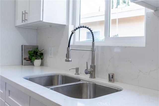 details featuring white cabinetry, sink, backsplash, and light stone counters