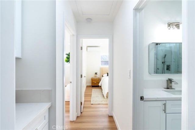 hallway featuring sink, a wall unit AC, and light wood-type flooring